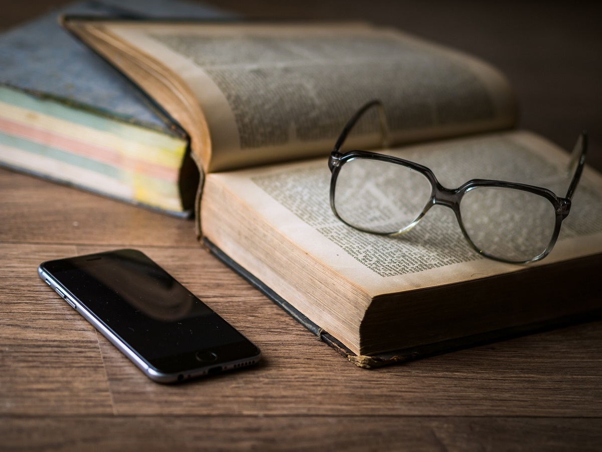 otevřená kniha, brýle na čtení a mobil